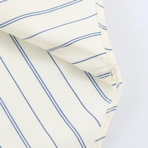 Macro detail of cream and blue striped cotton fabric showing premium stitching and texture