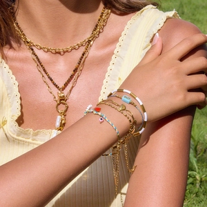 Détail de colliers de perles dorées et bracelets avec pendentifs cœur et mot LOVE