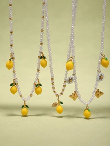 Dettaglio della collana con ciondoli a limone e margherita e perle artificiali