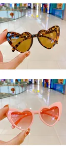 Detail view of heart-shaped kids sunglasses in leopard and pink frames with UV400 lenses
