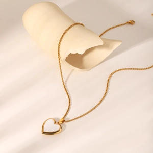 Gros plan du collier médaillon cœur en or 18K avec incrustation de nacre sur marbre