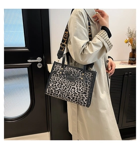 Fashionable leopard print tote bag with a patterned wide shoulder strap in a chic setting