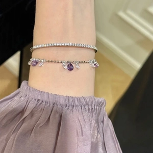 Detail of zircon water drop bracelet with purple stones and pavé set silver bangle