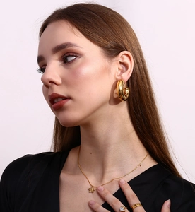 Close-up of gold plated stainless steel jewelry set featuring flower pendant and hoop earrings