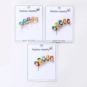 Detailed close-up of colorful enamel bird brooches with rhinestones on paper cards