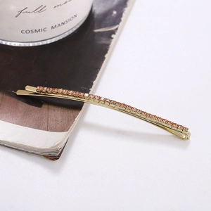 Close-up of golden hair clip with orange rhinestones on white magazine background