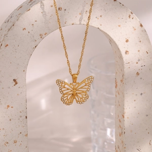 Macro shot of gold hollow butterfly pendant necklace with inlaid white zircon stones