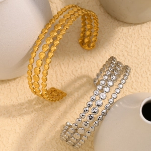 Macro detail of triple-layer gold and silver bead bangles with hammered texture