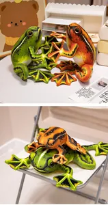 Realistic green and orange frog plush toys with black markings on a cozy desk display