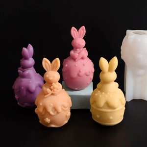 Detailed view of colorful 3D bunny candles and their translucent silicone mold on black back
