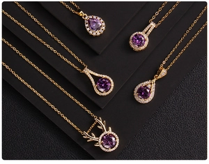 Detailed view of five golden necklaces with purple zircon pendants on a black background