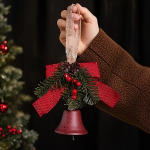 Detail of a red frosted Christmas bell with burlap bow, pine cones and red berries
