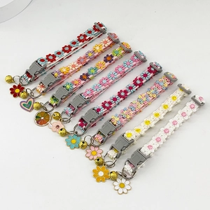 Detailed view of eight colorful lace pet collars with bells and enamel pendants