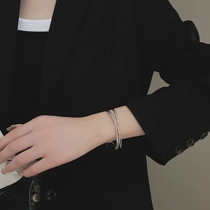 Detail shot of a minimalist silver layered wave bracelet on a model's wrist