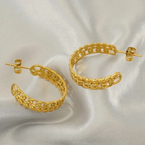 Elegant gold hollow C-shaped geometric earrings on soft silk fabric background