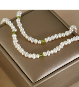 Detail of natural peridot and freshwater pearl necklace on a premium jewelry box
