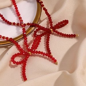 Macro shot of red faceted crystal bead necklace with gold accents and bow detail