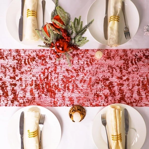Detailed top view of red and white mesh table runner with gold napkin rings on a table