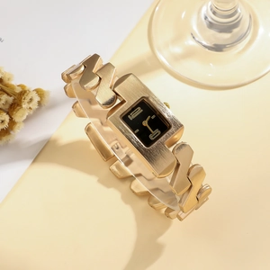 Detailed close-up of a luxury gold rectangular watch with a modern geometric metal band