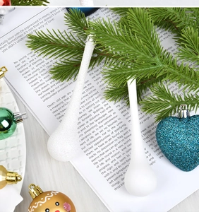 Close-up of white icicle-shaped Christmas ornaments on vintage script paper backdrop