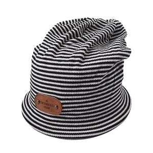 Detailed close-up of black and white striped knit beanie with vintage leather brand patch