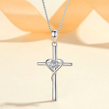 Detail shot of silver S925 heart cross necklace with a sparkling center stone on silk ribbon