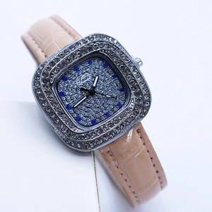 Detail of square silver rhinestone watch with blue glitter dial and beige leather strap