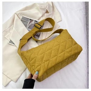 Detail of yellow quilted crossbody bag with wide shoulder strap and black buckle
