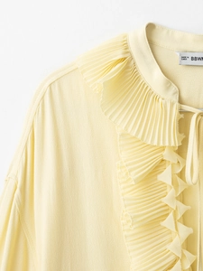 Detail of ruffled drawstring neckline on light yellow long sleeve chiffon blouse