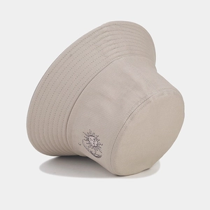 Detail of sun and moon line art embroidery on a beige cotton twill bucket hat
