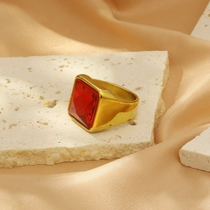 Macro detail of a gold titanium ring with a large square ruby on a stone surface