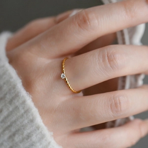 Macro shot of 18k gold plated twisted band ring featuring a sparkling central solitaire zircon