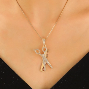 Gold scissors and comb pendant necklace with clear crystals on a sleek snake chain