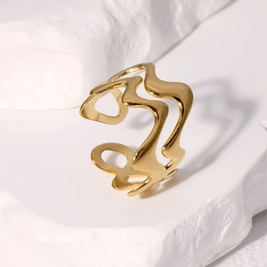 Bague ouverte irrégulière en acier inoxydable doré sur un fond en pierre blanche