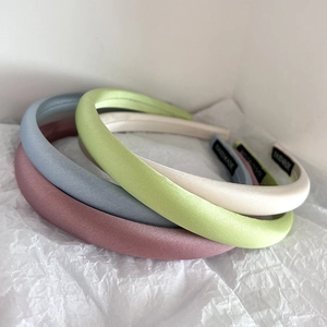 Close-up of four handmade satin headbands in pastel pink, blue, green and beige silk colors