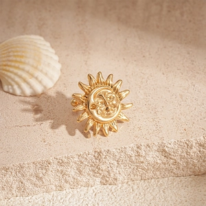 Detail of vintage gold sun earring with a face relief on textured stone backdrop