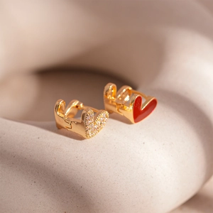 Macro view of gold heart earrings featuring red enamel and sparkling cubic zirconia stones