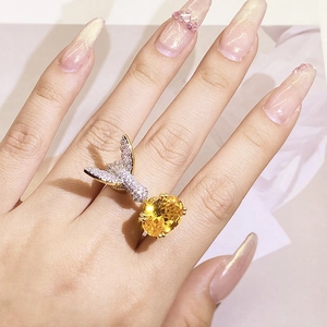 Detail of hummingbird ring featuring yellow oval gemstone and paved diamonds on hand
