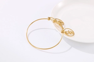 Adjustable gold plated steel bangle with hollow boy and girl silhouette charms