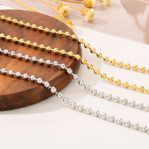 Close-up of gold and silver ball bead chains with metallic luster on wood base