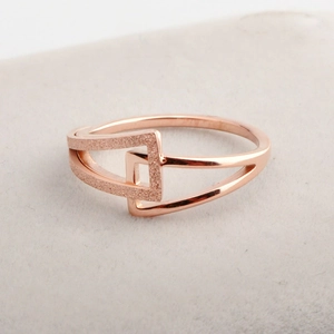Détail d'une bague géométrique or rose avec finitions mates et polies entrelacées