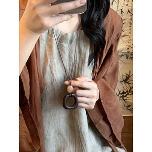 Close-up of retro wooden resin oval pendant with beige beads on a brown cord necklace