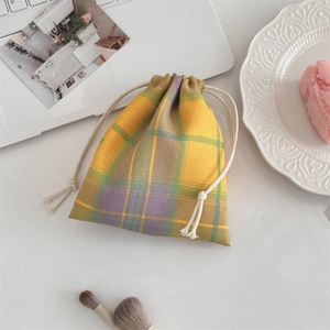Detailed view of checkered drawstring pouch on a desktop with cosmetics and accessories