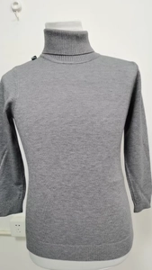 Detail of grey turtleneck sweater featuring ribbed texture on cuffs and neckline