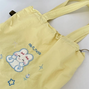 Close-up of cute bear embroidery and drawstring detail on pale yellow nylon tote bag