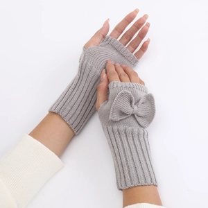 Close-up of grey knitted fingerless gloves with cute bow detail and soft wool texture