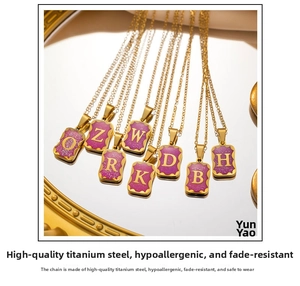 Close-up of golden titanium steel rectangle pendants with purple glitter and letters
