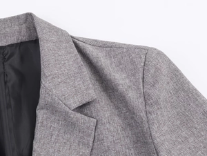Detailed close-up of herringbone blazer collar and padded shoulders with woven texture