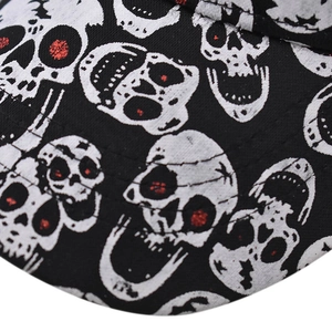 Makroaufnahme einer Totenkopf-Kappe mit roten Pailletten-Augen auf schwarzem Stoff