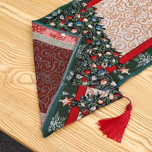 Detail of Christmas table runner with jacquard knit tree patterns and red tassel edge
